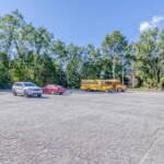 Outdoor vehicle storage featuring a compact car, school bus, and large SUV